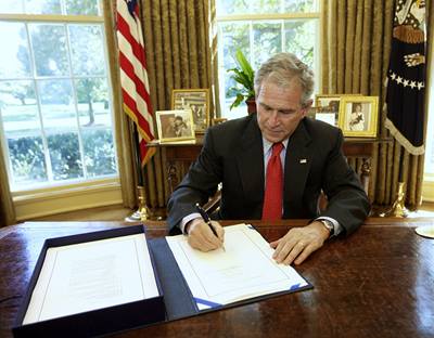 George Bush podepisuje návrh zákona na stabilizaci finanního systému.