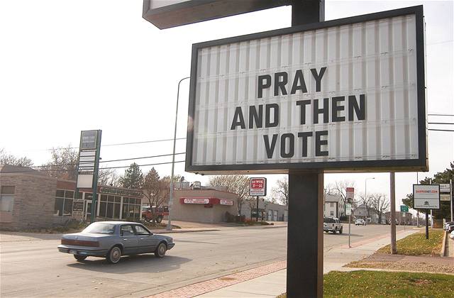 Pomodli se a potom vol, vyzývá billboard americké volie.