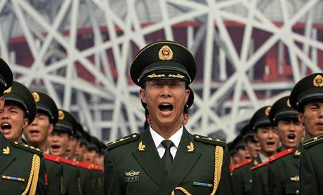 Vojáci stojí před národním stadionem v Pekingu, kde zahájí olympijské hry.