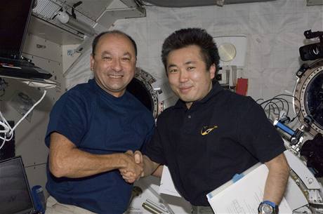 Komandér Mark Polanski si třese s japonským astronautem Koči Wakatou (vpravo).