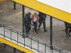 Policisté odvádjí pachatele ozbrojeného pepadení praské banky.