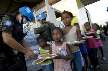Pracovníci OSN rozdávají hladovým dtem jídlo ve slumu Cite Soleil.