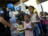 Pracovníci OSN rozdávají hladovým dtem jídlo ve slumu Cite Soleil.