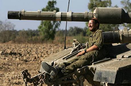 Izraelský voják odpočívá na tanku Merkava u hranic s pásmem Gaza.
