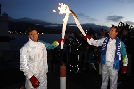 Kalifornský guvernér Arnold Schwarzenegger (vpravo) pedává olympijskou pochode slavnému britskému bci Sebastianu Coeovi.