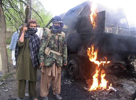 Vzbouenci z hnutí Taliban pózují u znieného nmeckého armádního vozidla
