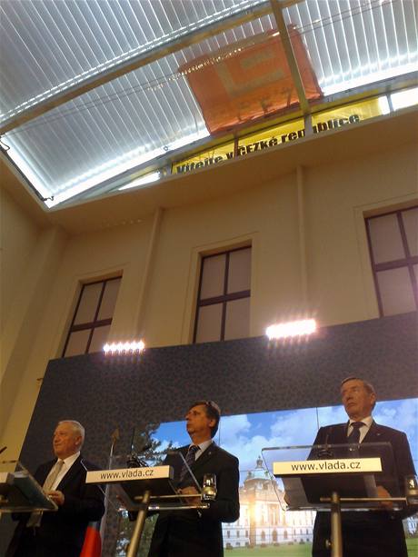 Ministi a premir Jan Fischer (uprosted) 3. kvtna na tiskov konferenci vldy. Nad nimi ekologit aktivist, kte vylezli na stechu Strakovy akademie