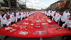 Stovka lidí nese 44 metr� dlouhý prapor s odznaky ze sibi�ských m�st p�i oslavách konce druhé sv�tové války v Krasnojarsku