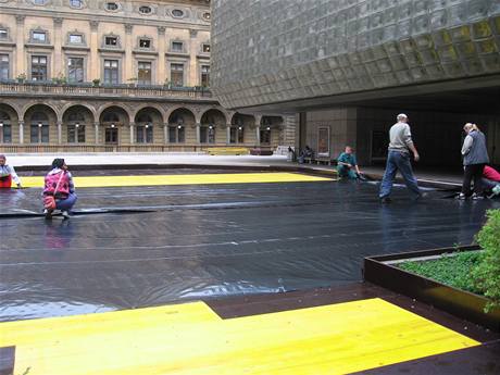 Dělníci na prostranství mezi Národním divadlem a Novou scénou instalují trávník. 