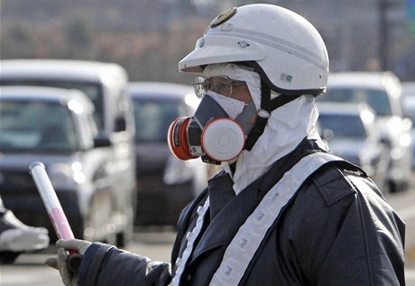 Japonský policista se chrání respirátorem pi evakuaci obyvatel po hávrii v jaderné elektrárn v prefektue Fukuima.