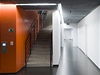 Kontrast oranové s edou. Interiér budovy architektury VUT psobí kompaktn a prost.