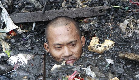 Obyvatelé slumu se po niivém poáru brodí mezi troskami a odpadky. 
