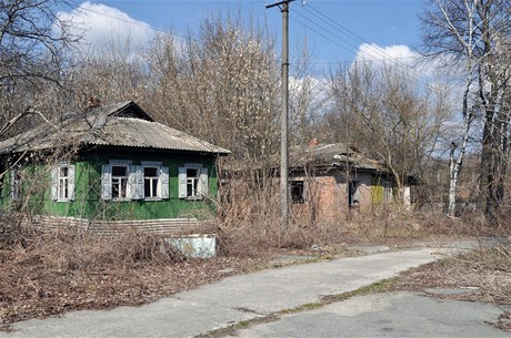 ernobyl. Na snmku zjevn udrovan chaloupka vedle rozpadajcho se domu na okraji msta. 