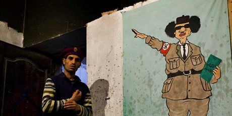 Rebel v Benghází ped portrétem, který Kaddáfího zobrazuje jako Hitlera