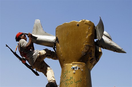 Povstalec na známém monumentu zlaté psti drtící americký letoun v Kaddáfího opevnném sídle. 