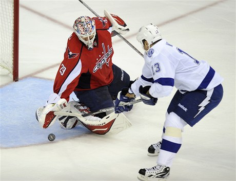 eský branká Tomá Vokoun z Washingtonu Capitals vyráí puk, který se snaí dostat do brány obránce Tampy Pavel Kubina  