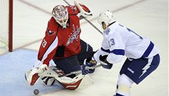 eský branká Tomá Vokoun z Washingtonu Capitals vyráí puk, který se snaí dostat do brány obránce Tampy Pavel Kubina  