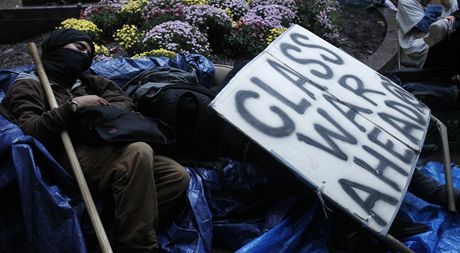 Spje svt ke tídní válce? Mnozí úastníci protest proti sociální nerovnosti jsou o tom pesvdení. Na snímku jeden z nich spí vedle transparentu hlásajícího tuto hrozbu v Zuccotti Parku v New Yorku.