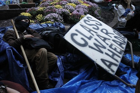 Spje svt ke tídní válce? Mnozí úastníci protest proti sociální nerovnosti jsou o tom pesvdení. Na snímku jeden z nich spí vedle transparentu hlásajícího tuto hrozbu v Zuccotti Parku v New Yorku.
