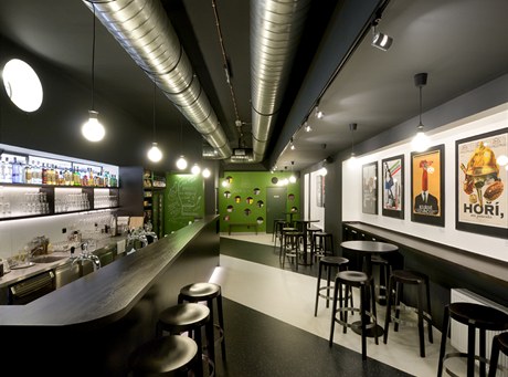 Prodlouený bar, odhalené technické instalace, pouze ti barvy a podlaha inspirovaná filmovou klapkou.