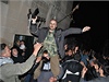 Úastníci veerního prostesu vyzvihují bývalého vládního vojáka, který dezertoval stranu prostestujících. 30. ledna 2012