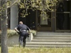 Oaklandský policista míí se zbraní v ruce ke vchodu do oaklandské univerzity Oikos.