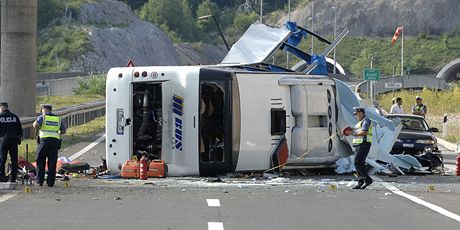 Havarovaný autobus leí na boku, policie zkoumá okolí nehody.