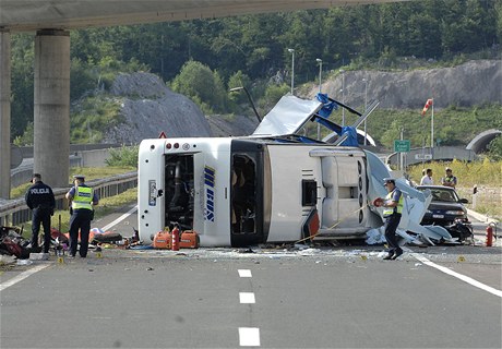 Havarovaný autobus leí na boku, policie zkoumá okolí nehody.