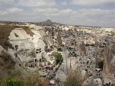 Göreme, msto vytesané do skal. Na obzoru se tyí hrad v Uchisaru.