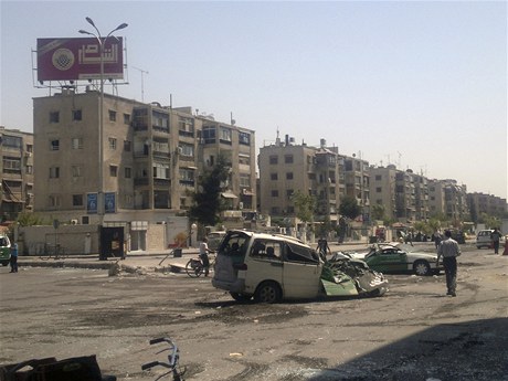 Syané procházejí kolem zniených aut v Damaku.