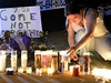 Dívka zapaluje svíku za obti páteního masakru v Denveru.