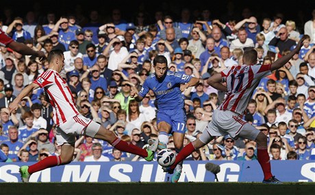 Fotbalista Chelsea Eden Hazard (uprosted) v obklíení hrá Stoke City Geoffa Camerona (vlevo) a Ryana Shawcrosse