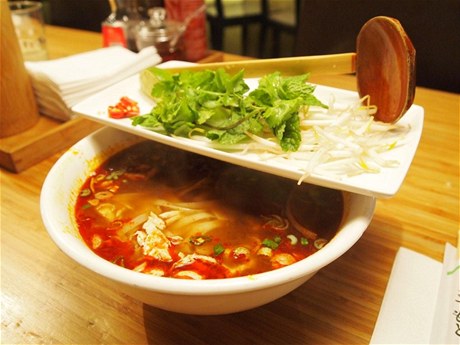 Vietnamská polévka pho, doplněná limetkou, chilli papričkami, bambusovými výhonky a čerstvými bylinkami.
