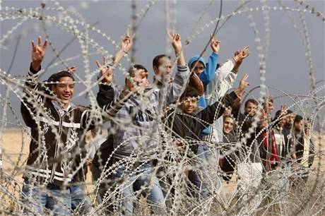 Palestinci gestikulují na izraelské vojáky na jihu pásma Gazy a �idovským státem.  