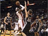 Miami Heat LeBron James (uprosted v bílém dresu) skóruje zatímco mu brání hrá San Antonia Spurs Tiago Splitter (22)