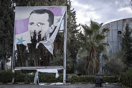 Písluník Svobodné syrské armády se modlí u streného portrétu diktátora Baára Asada.