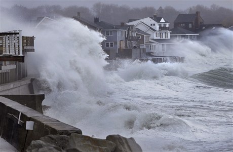 Vlny se lámou o domy stojící na břehu moře v Massachusetts.
