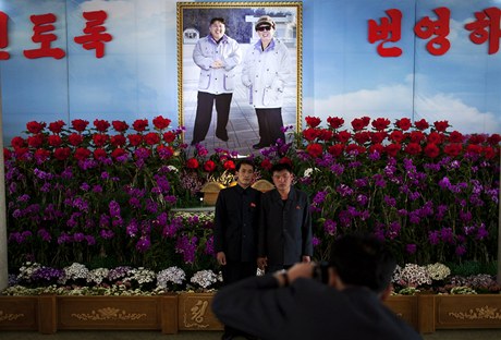 Mui pózují ped fotografií Kim ong-una a jeho otce Kim ong-ila. Propaganda z nich dlá "bohy".