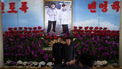 Mui pózují ped fotografií Kim ong-una a jeho otce Kim ong-ila. Propaganda z nich dlá "bohy".