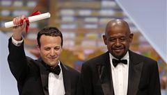 Reisér Amat Escalante mává davu po získání ceny za nejlepího reiséra za film Heli, vedle stojí herec Forest Whitaker 