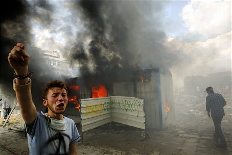 Protivládní demonstrant volá o pomoc pi haení zapáleného kontejneru na námstí Taksim. 