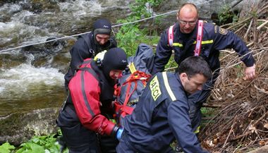 Hasiči odnáší tělo 43letého muže z Prahy, který utonul při povodních.
