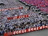 Ticíce lidí pochodují metropolí Pchjongjangem.