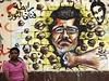 Jeden z demonstrant sedí ped graffiti, které zesmuje Mursího