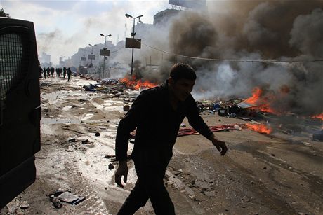 Mu utíká hoícími ulicemi Káhiry, v pozadí poádková policie