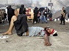Zranný demonstrant  v káhirských ulicích. Policisté a vojáci v pozadí vyklízejí tábor protestujících.