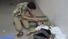 Muž ošetřuje chlapce zasaženého chemickým útokem