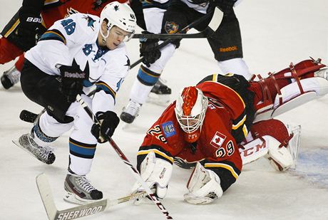 eský hokejista San José Sharks Tomá Hertl (vlevo) a branká Calgary Flames Reto Berra 