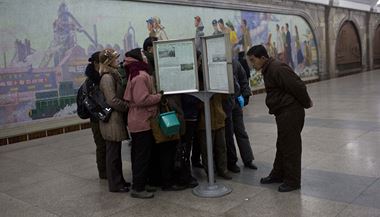 Severokorejci se v pchjongjangskm metru shromauj kolem vyvench novin, kter informuj o odstrann ang Song-tcheka