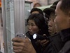 Severokorejci se v pchjongjangském metru shromaují kolem vyvených novin, které informují o odstranní ang Song-tcheka